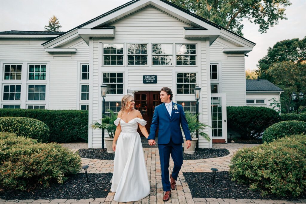 Bride and groom holding hands at the outside of the Wellers Carriage House in Southeastern Michigan
