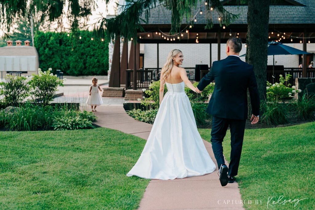 Couple walking with flower girl outside of Pine Knob Carriage House