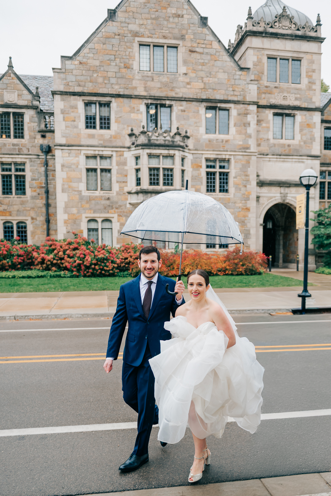 Bride and groom holding umbrella outside Michigan League Ballroom